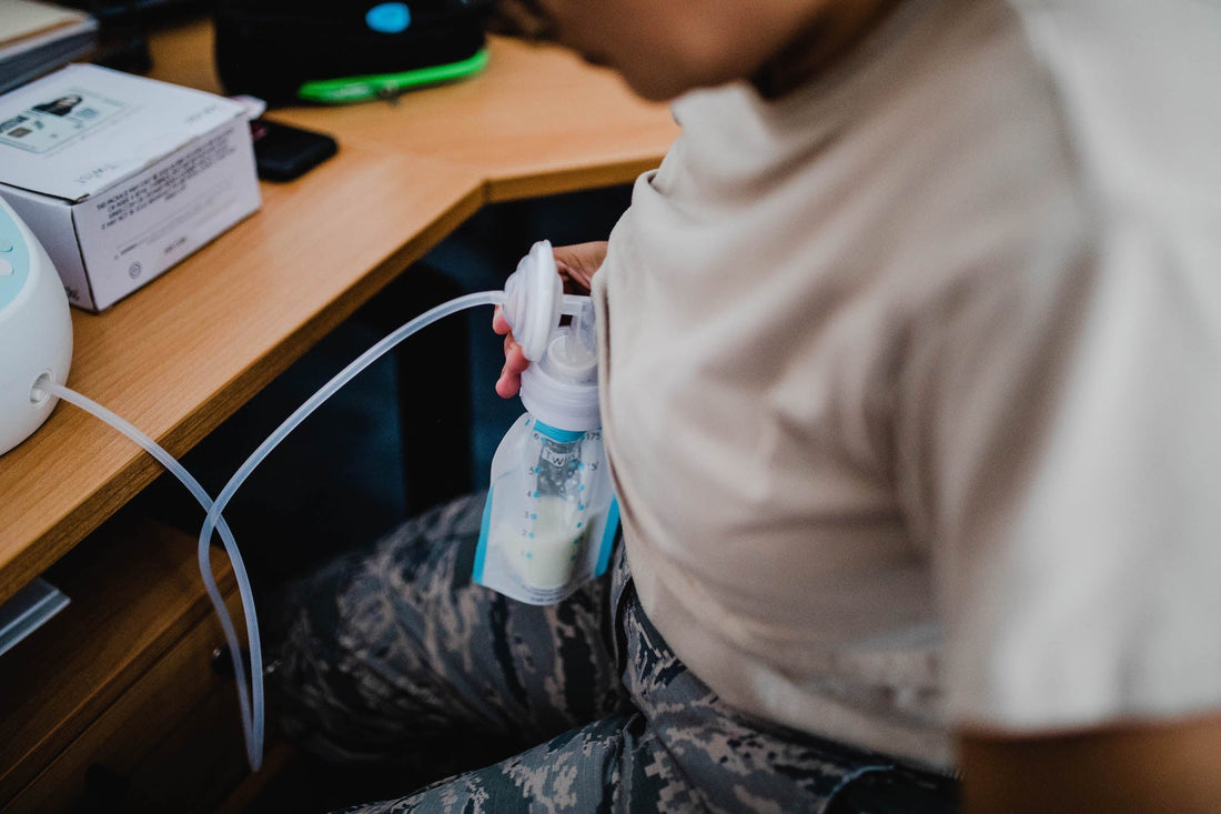 An image of a woman pumping directly into a Kiinde pouch while sitting at a desk.