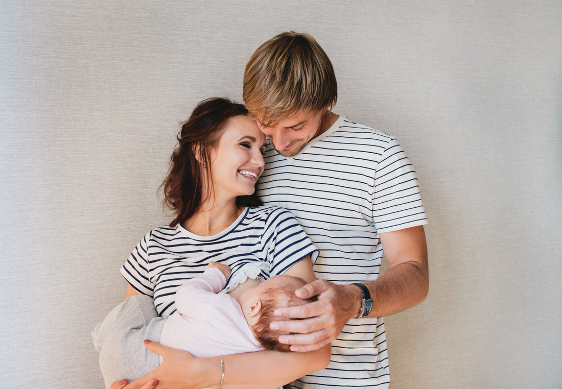 Dad huggging mom from behind while mom holds baby