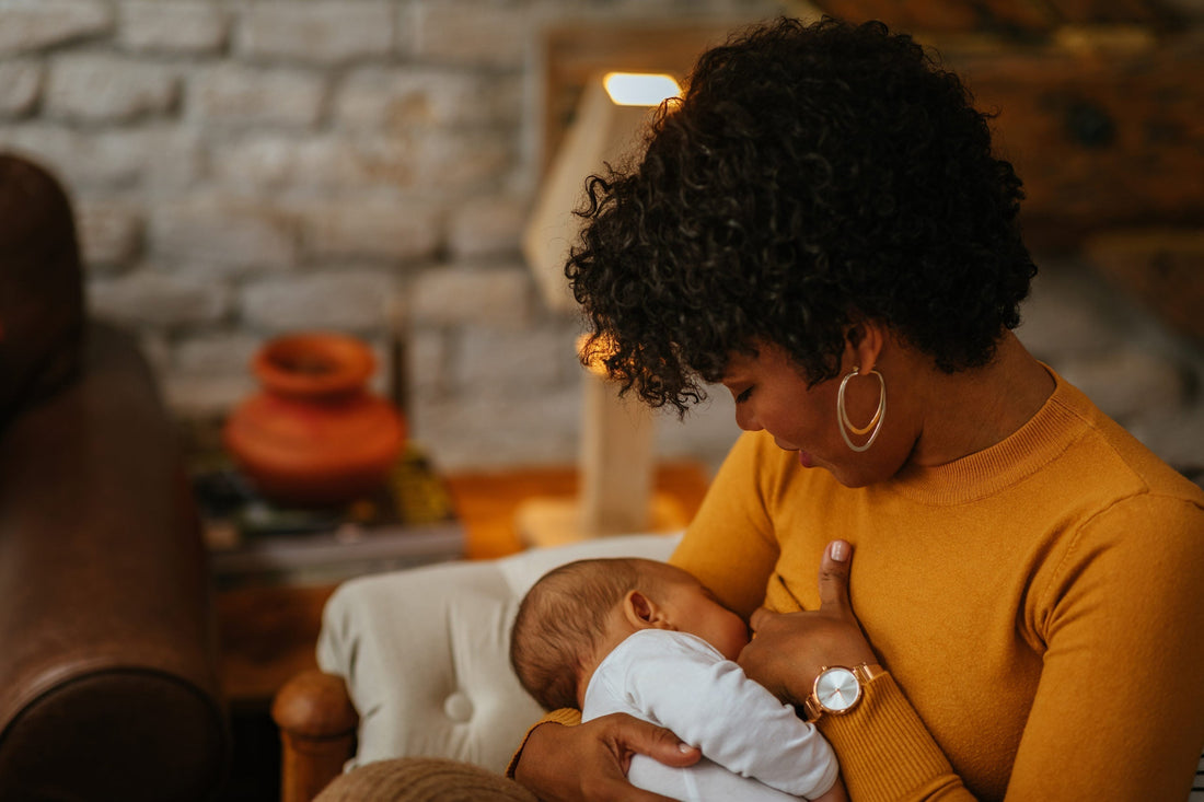 Woman in orange long sleeve shirt holding baby to her chest