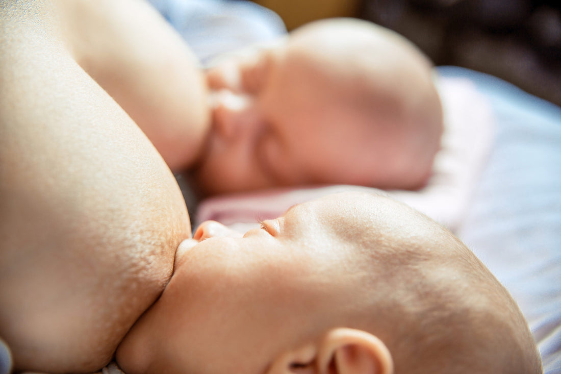 Two babies breastfeeding with one baby latched on each breast