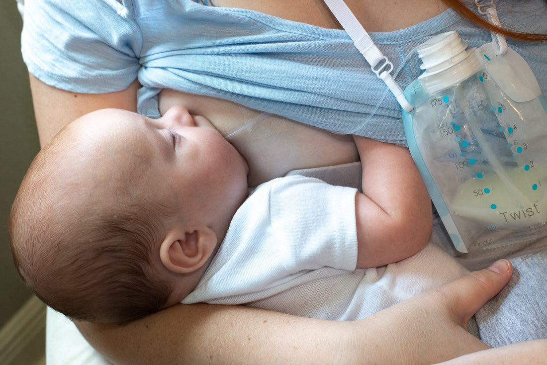 Image of a mother breastfeeding a baby while a Kiinde pouch is handing on a lanyard around the mother's neck.